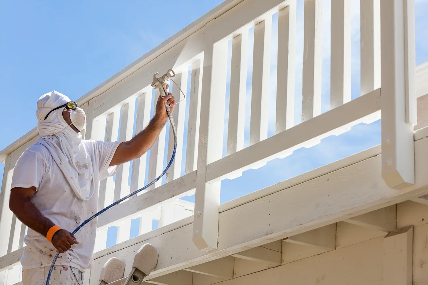 Deck Railing Painting Rodgers Painting painter spraying white paint on a deck railing