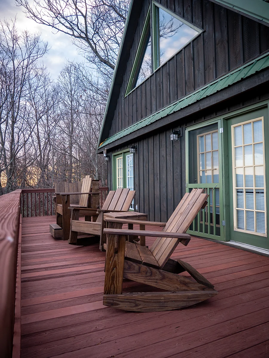 Deck Staining Stained red wood deck with Adirondack chairs beside a dark sided cabin
