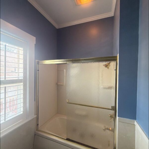Bathroom painted a soft periwinkle blue with white trim and glass shower doors