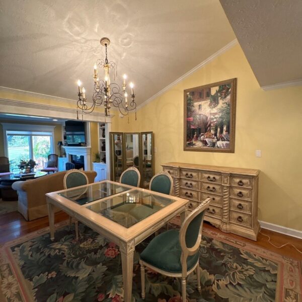 Formal dining room with warm yellow walls, white crown molding and a chandelier