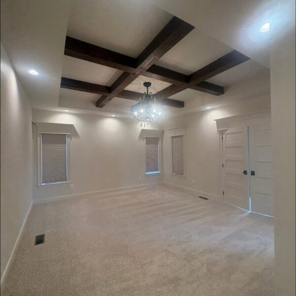 Empty room with painted coffered ceiling beams and fresh light gray walls