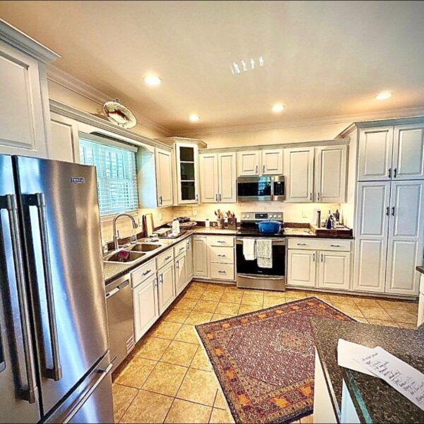Cream Kitchen Cabinets Wide view of a kitchen with painted cream cabinets and granite counters