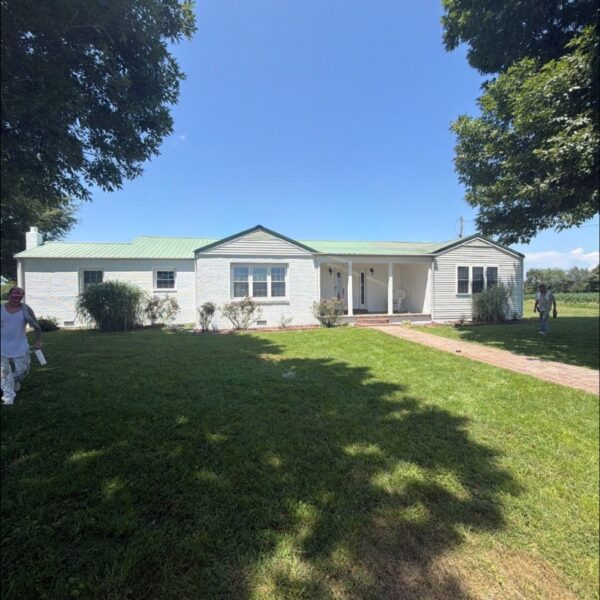 White ranch house exterior freshly painted, with a green lawn