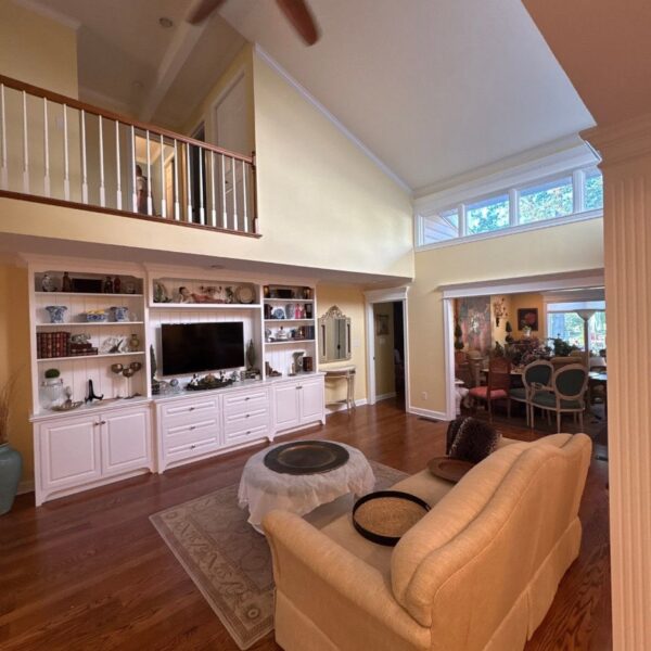 Vaulted living room with painted white built in shelves and loft balcony railing